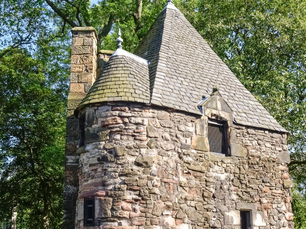 istock Old stone building with slate roof in front green foliage 1440079220