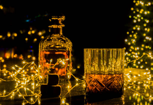 glass of whiskey with Christmas lights in the background stock photo
