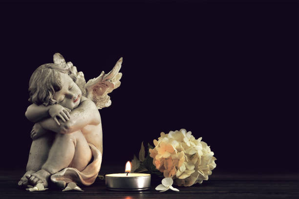 istock Angel, funeral flower and candle on black background with copy space 1440095573