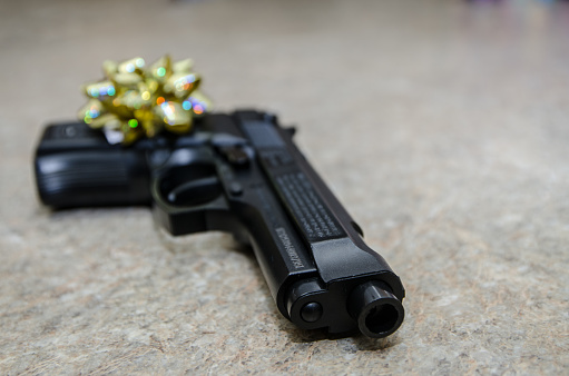 Golden gift bow on handgun