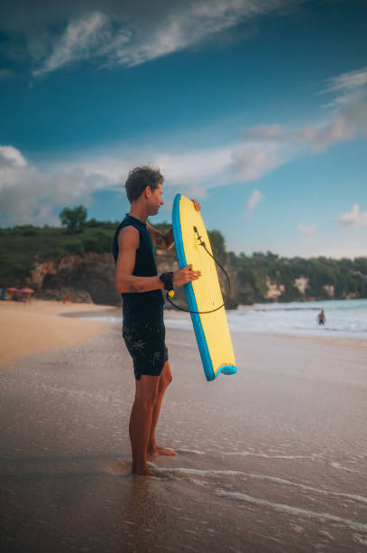 Catch the wave Handsome young man with a bodyboard on the beach body board stock pictures, royalty-free photos & images