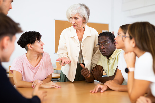 Senior woman participating in English language speaking club with multiracial group of people
