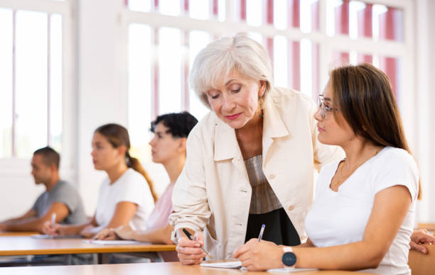 istock Elderly female teacher helping to solve problem to young girl student 1440098919