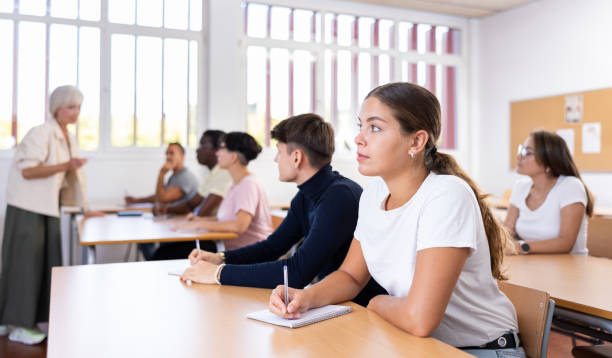 istock Young girl listening to lecture and taking notes in classroom 1440098930