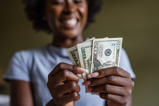 Portrait of an African American woman looking very happy while counting cash