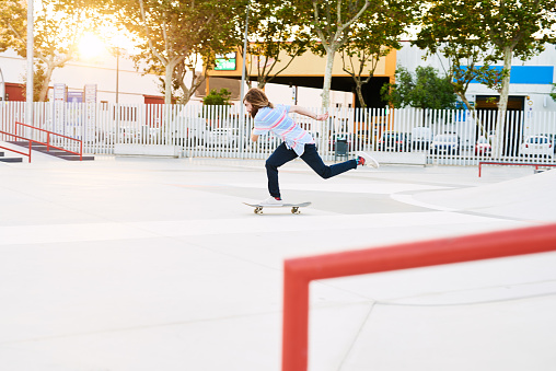 Side view of young stylish skateboarder riding in park