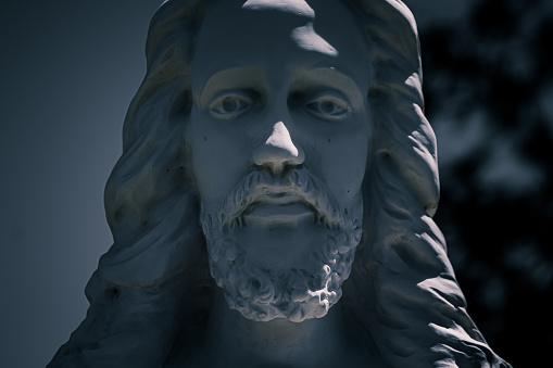 Close up of Jesus Christs Face of a stone grave marker at a cemetery