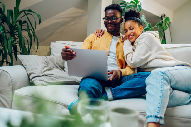 istock Multiracial couple using laptop while sitting on a sofa at home 1440109690