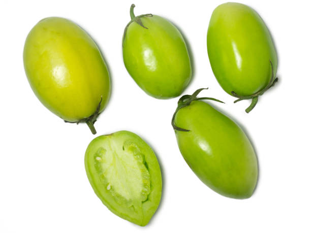 Green tomatoes on a white background. The concept of an unripe vegetable. Salt preparation. Salting product. Healthy food. Place for writing text. An unripe fruit picked from a bush.