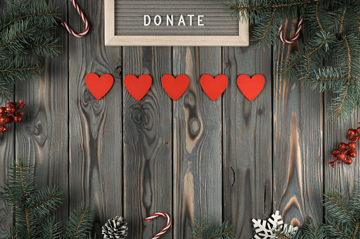 Donation abstract composition with red heart garland on dark wooden Christmas decorative background. Charity, donation and philanthropy. Helping hand in holidays. Flat lay, copy space, mockup