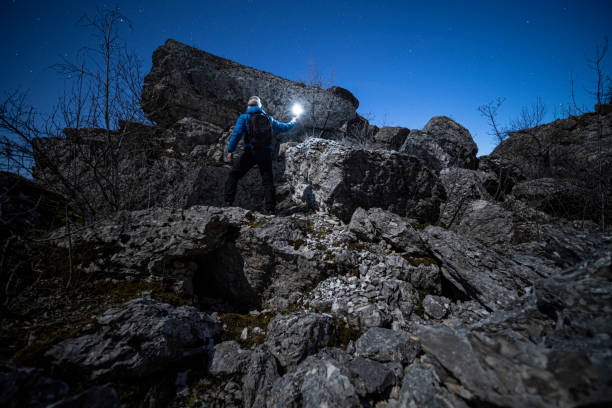 istock Man climbing with light at night in a rocky mountain cave. 1440110203