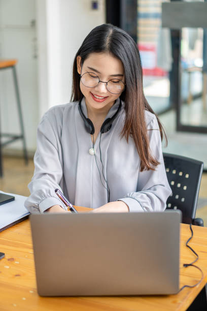 concetto di studio autonomo
donna asiatica che indossa le cuffie, guarda il laptop, si diverte con l'apprendimento online con videochiamata con tutor. ascolta la narrazione audio guarda il webinar - financial occupation audio foto e immagini stock