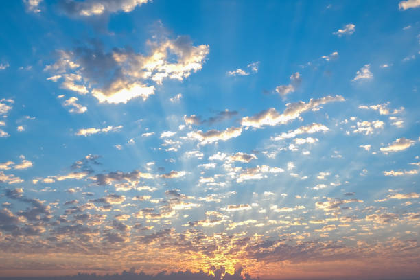 Blue sky with twilight clouds. The sun is setting over the horizon. Yellow dawn. Red sunset. Pink clouds.
