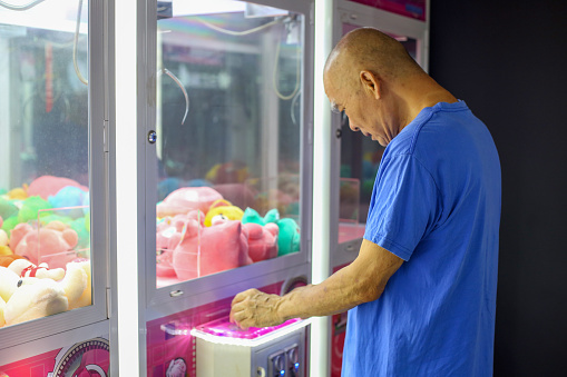 An Asian senior man is enjoying time at game arcade.