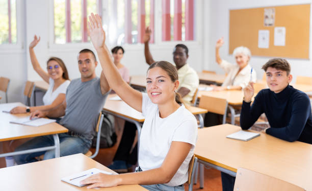 istock Smiling young girl student raising hand to answer during lecture 1440126502