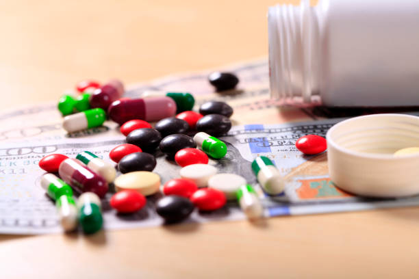 istock Pharmacy background. Pills on a banknote isolated on a white background. Different types of capsules on dollars banknote. 1440127366