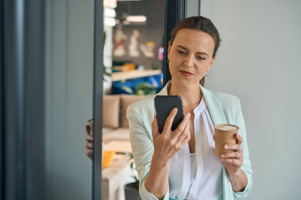 istock Businesswoman with smartphone drinking coffee at work 1440128568