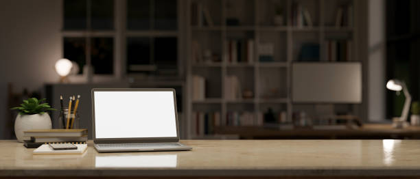 istock Marble tabletop with laptop mockup and copy space over blurred modern dark office workspace at night 1440130118