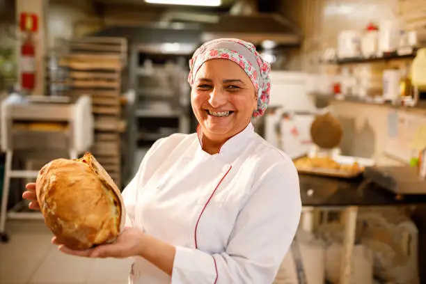 Photo of Happy baker showing a loaf of bread