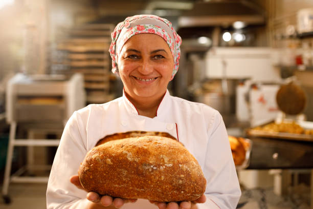 istock Smiling baker showing a loaf of rustic bread 1440131524