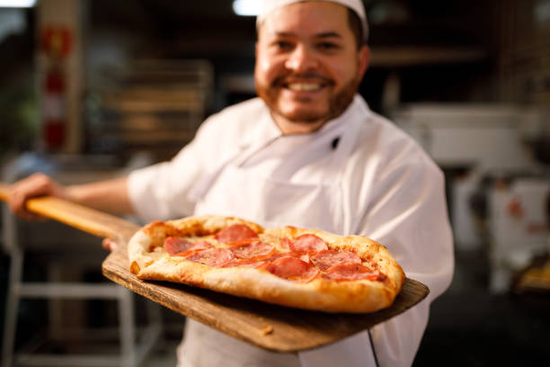 istock Smiling baker showing a freshly baked pizza 1440131870