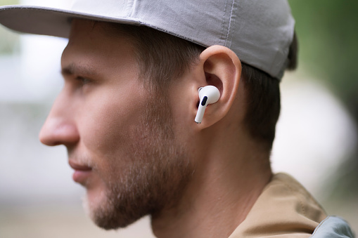 close up male person using wireless earphones and listen to the music