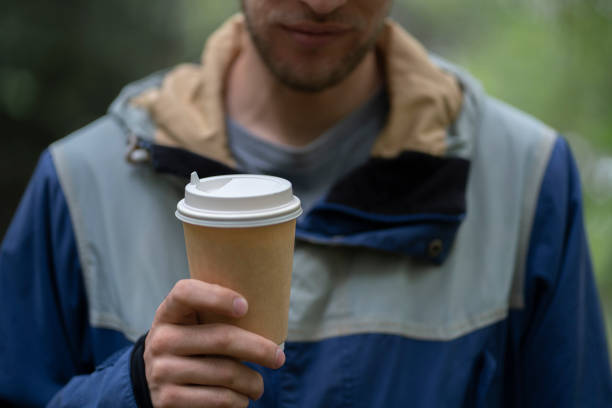 person holding take away paper cup with hot drink