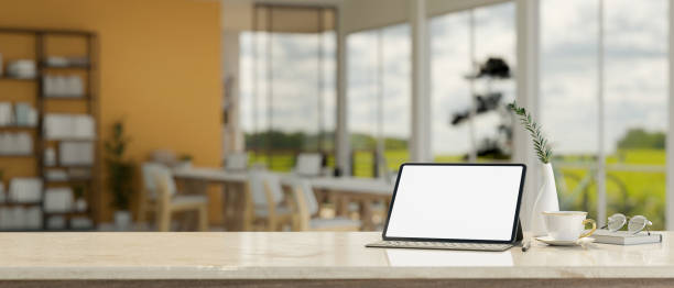 istock Mock up tablet with copy space over blurred modern dark office workspace background. 1440132493