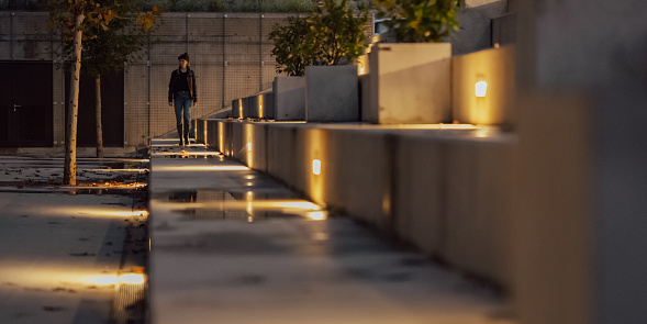Photo of a woman walking on big concrete steps in a city at night.