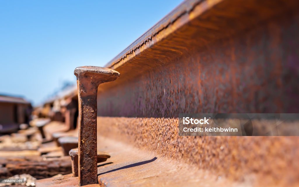 Railroad spike up close Side view of a railroad spike that hasn’t been hammered down as other spike, the spike is several inches above the edge of the railroad track.  Both the rail and spike are worn and covered in large amounts of rust. Abandoned Stock Photo