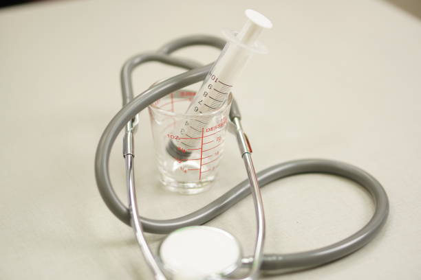Medical: Stethoscope with volumetric measuring cup and syringe.