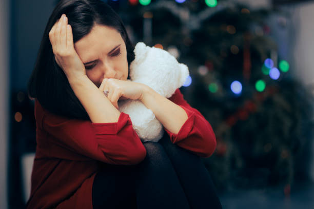 istock Sad Depressed Woman Sitting Alone by a Christmas Tree 1440144017
