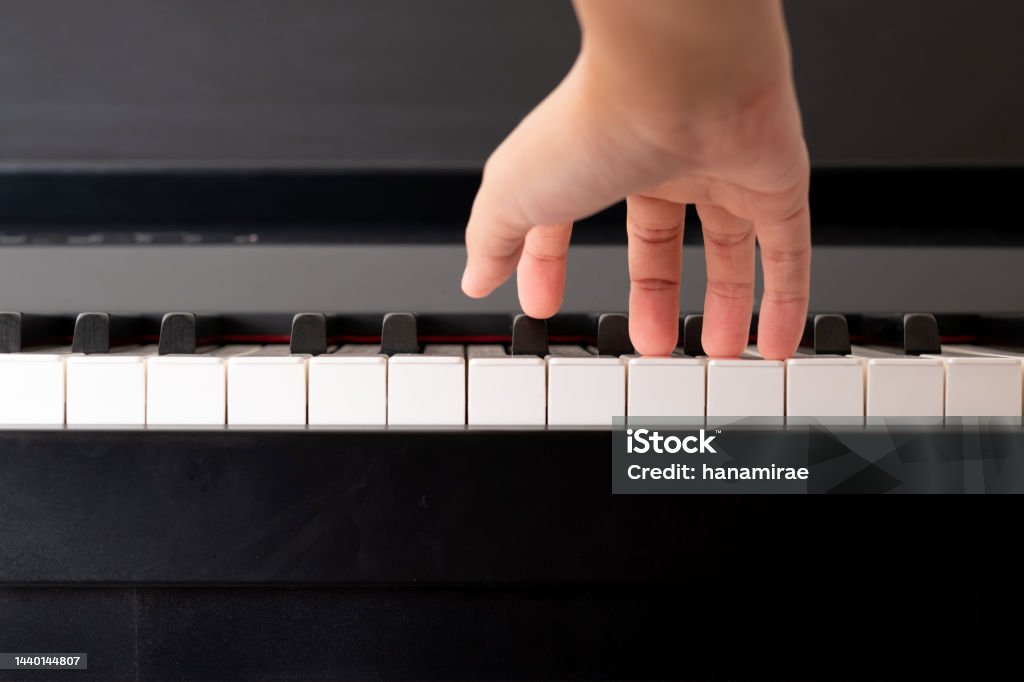Closeup to adult compose right hand and press the piano key. Practicing music instrument. Finger Stock Photo
