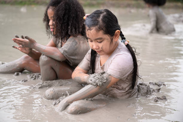 istock Funny Asia kid girl playing in mud puddle 1440149460