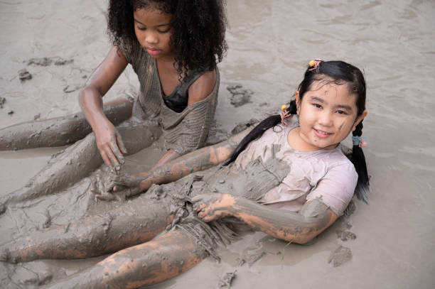 istock Funny Asia kid girl playing in mud puddle 1440149468