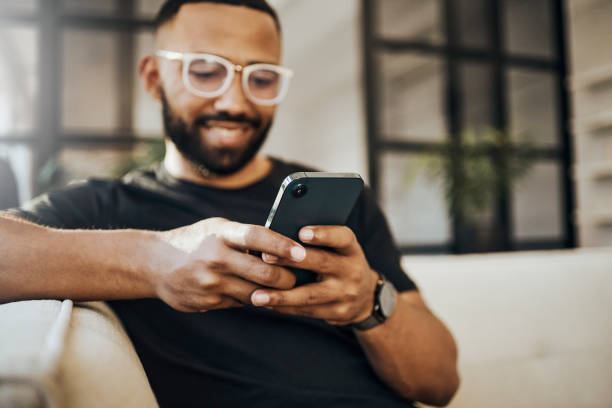 glücklicher mann, social-media-telefon und wohnzimmer entspannen, smartphone und online-kommunikation tippen, benachrichtigung lesen und web auf dem sofa. smile guy hände, mobile verbindung und heimnetzwerktechnologie - smart phone telephone human hand mobile phone stock-fotos und bilder