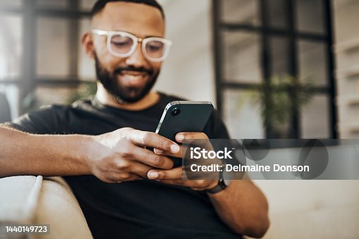 istock Happy man, social media phone and living room relax, typing smartphone and online communication, reading notification and web on sofa. Smile guy hands, mobile connection and home network technology 1440149723