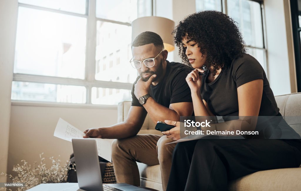 Laptop, paper and couple with mortgage, bills or loans doing financial calculations together at home. Computer, finance and young people from Puerto Rico paying debt with online internet banking. Financial Loan Stock Photo