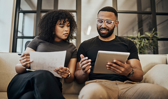 Tablet, documents and finance with a black couple in their home to manage savings, investment or budget. Money, paper and accounting with a man and woman planning for financial growth in their house