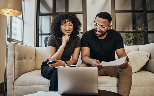 Black couple, online banking and finance documents for bill payments at home. Young people, laptop and paperwork to pay life insurance will and accounting payments. Digital ecommerce and family loan