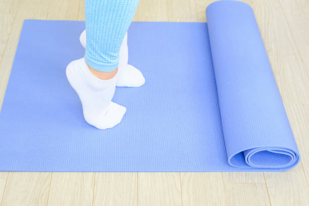 istock Female legs doing exercises lifting on toes close-up on blue background. 1440151850