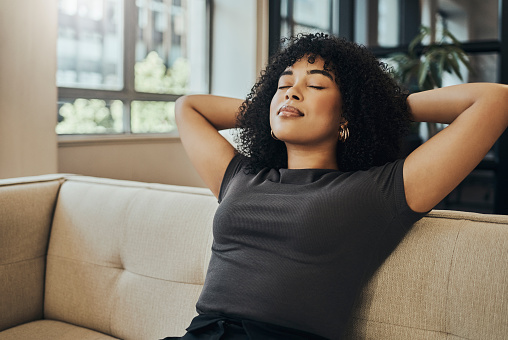 Wellness, peace and black woman relax on sofa for health lifestyle, stress relief or healthy mindset. Calm, dream and young girl sleeping in living room for rest, comfort break or freedom of the mind