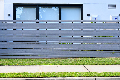 Grey wooden horizonal slat fence in front of a house