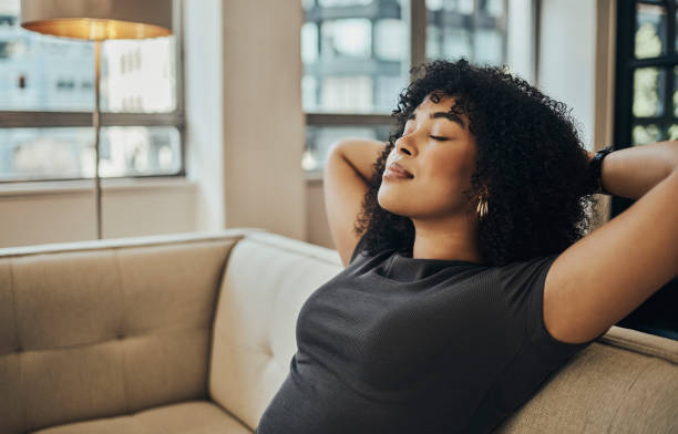 Relax, rest and woman on sofa with eyes closed at home in city apartment. Happy, healthy and stress free, girl from Brazil smiling, relaxing and thinking alone on couch, calm zen and happy nap time. relájese, descanse y la mujer en el sofá con los ojos cerrados en casa en el apartamento de la ciudad. feliz, saludable y libre de estrés, chica de brasil sonriendo, relajándose y pensando sola en el sofá, zen tranquilo y feliz hora de la siesta.