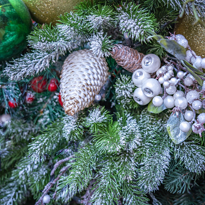 Fragment of a Christmas tree covered with snow with toys