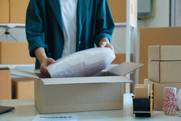 istock Young entrepreneur packing product in mailing box for shipping. 1440156093