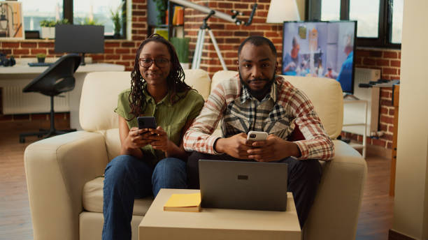 istock Life partners using smartphones together sitting at home 1440156811