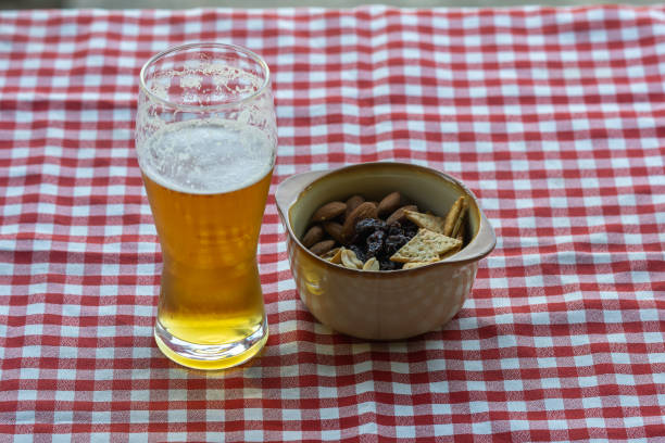 bicchiere di birra sul tavolo con una tovaglia a scacchi e snack - healthy eating eating food and drink beer nuts foto e immagini stock