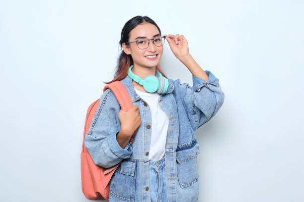 istock Smiling young pretty woman wearing a backpack touching eyeglasses isolated on white background 1440163316