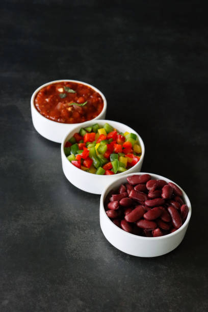 Image of three Mexican salsa dips in white dishes for tortillas / fajitas / tacos, with red kidney beans, chopped bell peppers stock photo